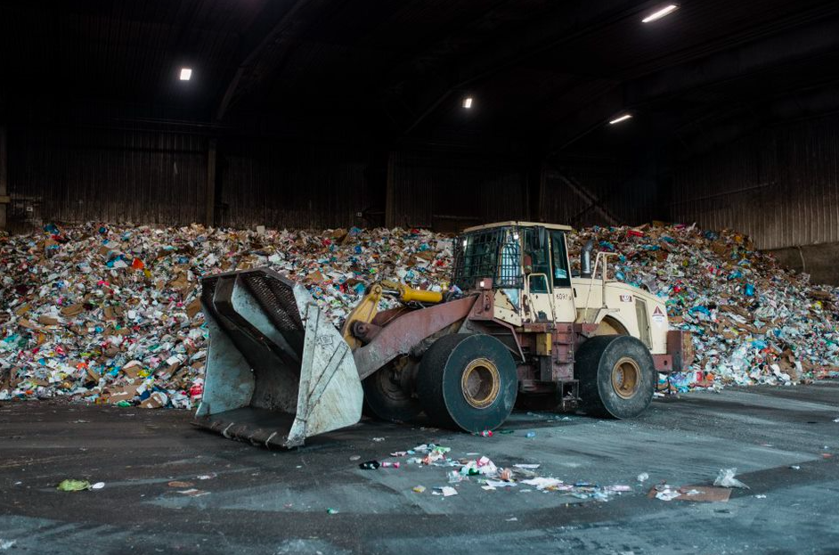 Miller Waste front loader in front of a large pile of waste. 