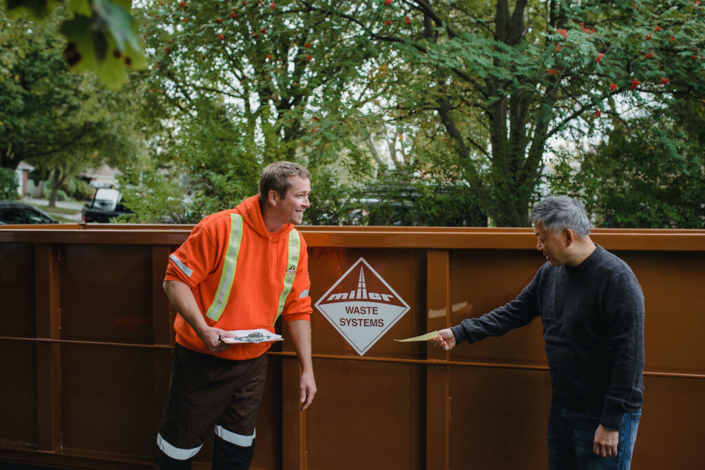 A Miller Waste Systems staff member dropping off a residential dumpster bin to a customer.
