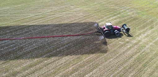 A tractor applies digestate as certified organic fertilizer on a farm 