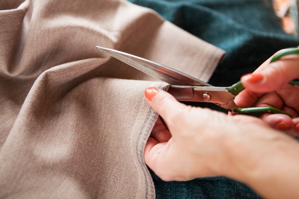 Someone with scissors cutting into a piece of fabric. 