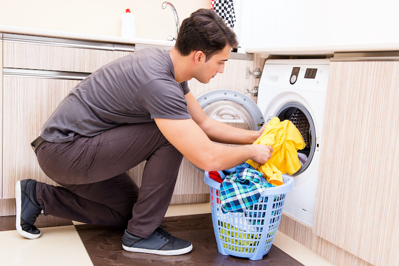 A man putting clothes into a washing machine.