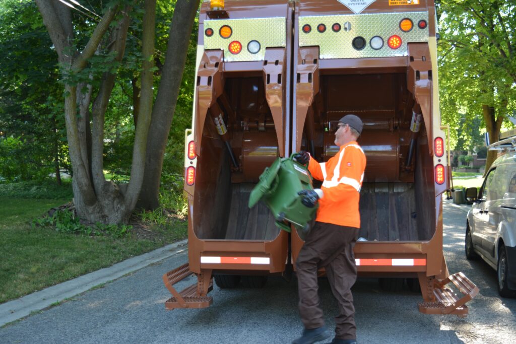 A Miller Waste Collection Service Representative loads organic waste into a dual stream garbage truck.
