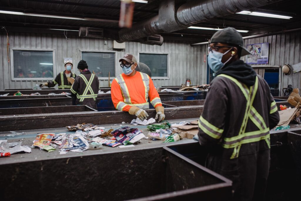 Works manually sort municipal and commercial waste on a conveyor belt.